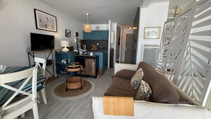 A modern living room with a sofa, a dining table, and a kitchen area. - Charming 2-room apartment with pool in Hendaye, near port (Hendaye)