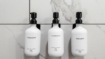 Three white bottles of personal care products on a tiled wall.