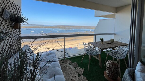A balcony with a view of a beach and ocean, a small table, two white chairs, and a sofa. - Arcachon - 2-Bedroom Apartment with Terrace, Sea View and Parking (Arcachon)