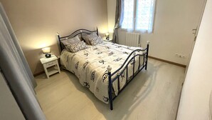 A bedroom with a bed, bedside tables, a window with curtains, and a radiator. - Family home near beach with WiFi and pets allowed (La Tranche-sur-Mer)
