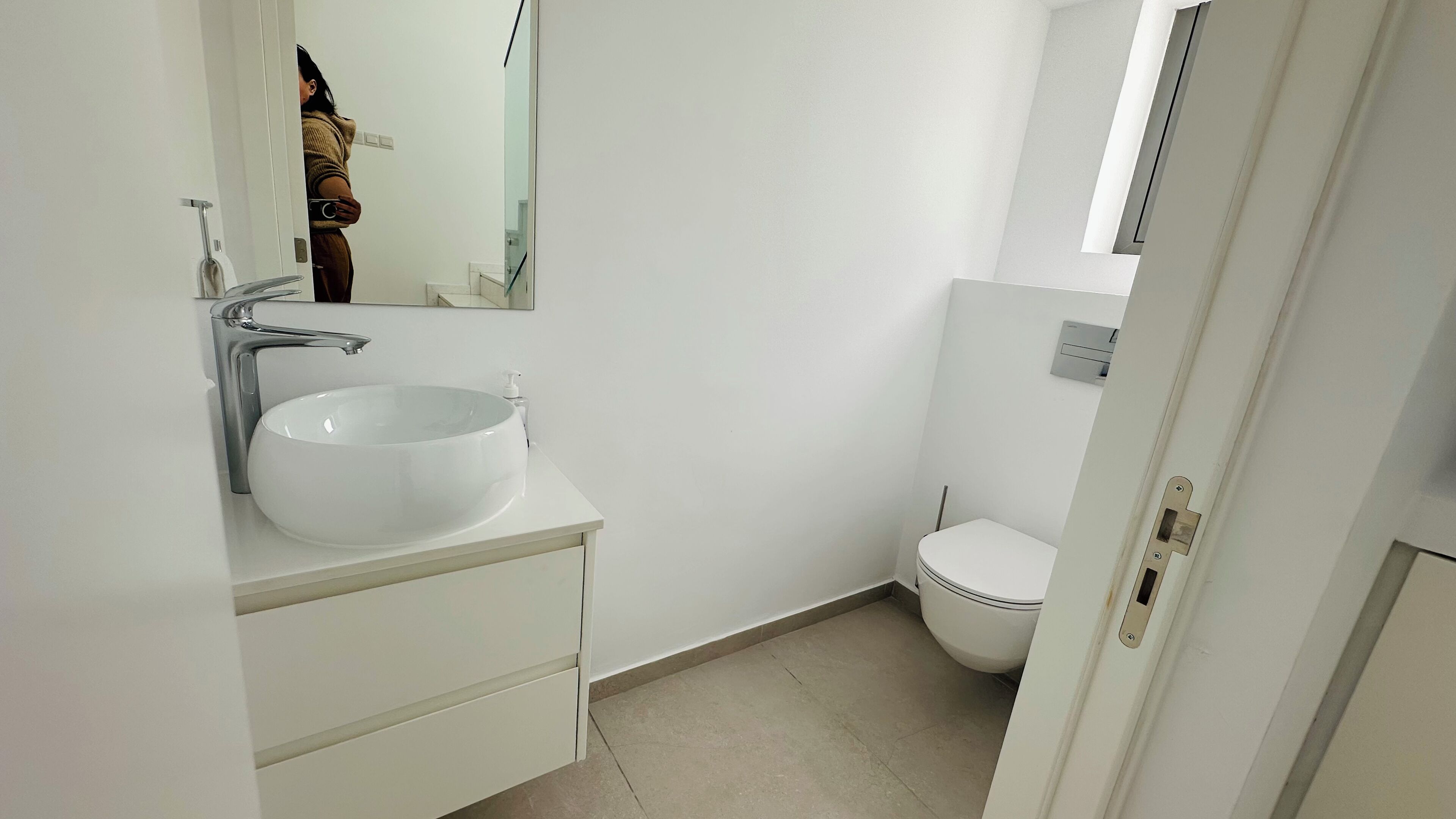 Een kleine, schone badkamer met een witte wasbak, spiegel en toilet.
