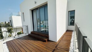 A modern building with a wooden deck, a glass door, and a white exterior. - Luxury 4 bdr Villa Nerida (Chlorakas)