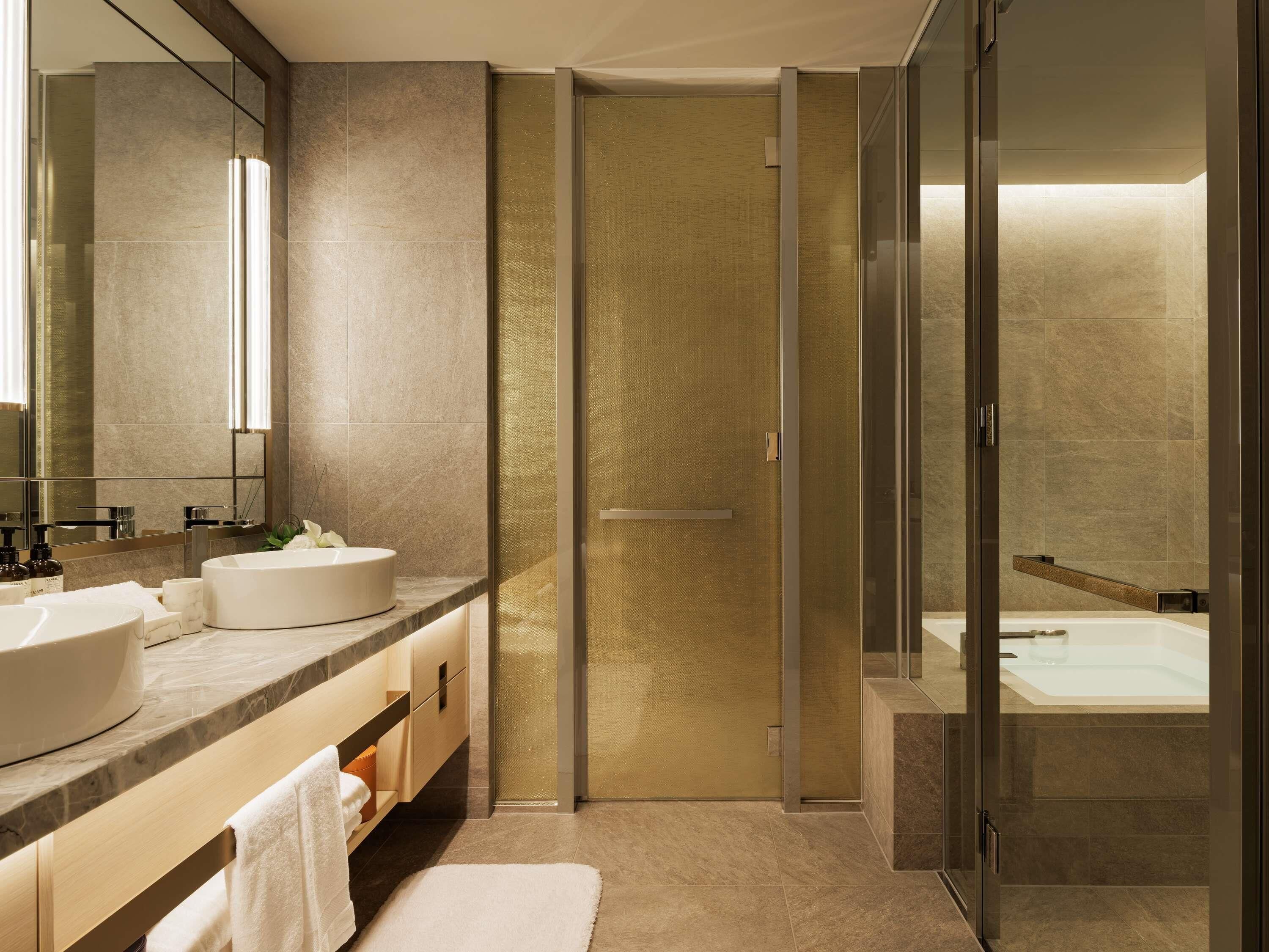Un baño moderno con dos lavamanos, un espejo grande, cabina de ducha de vidrio y bañera.