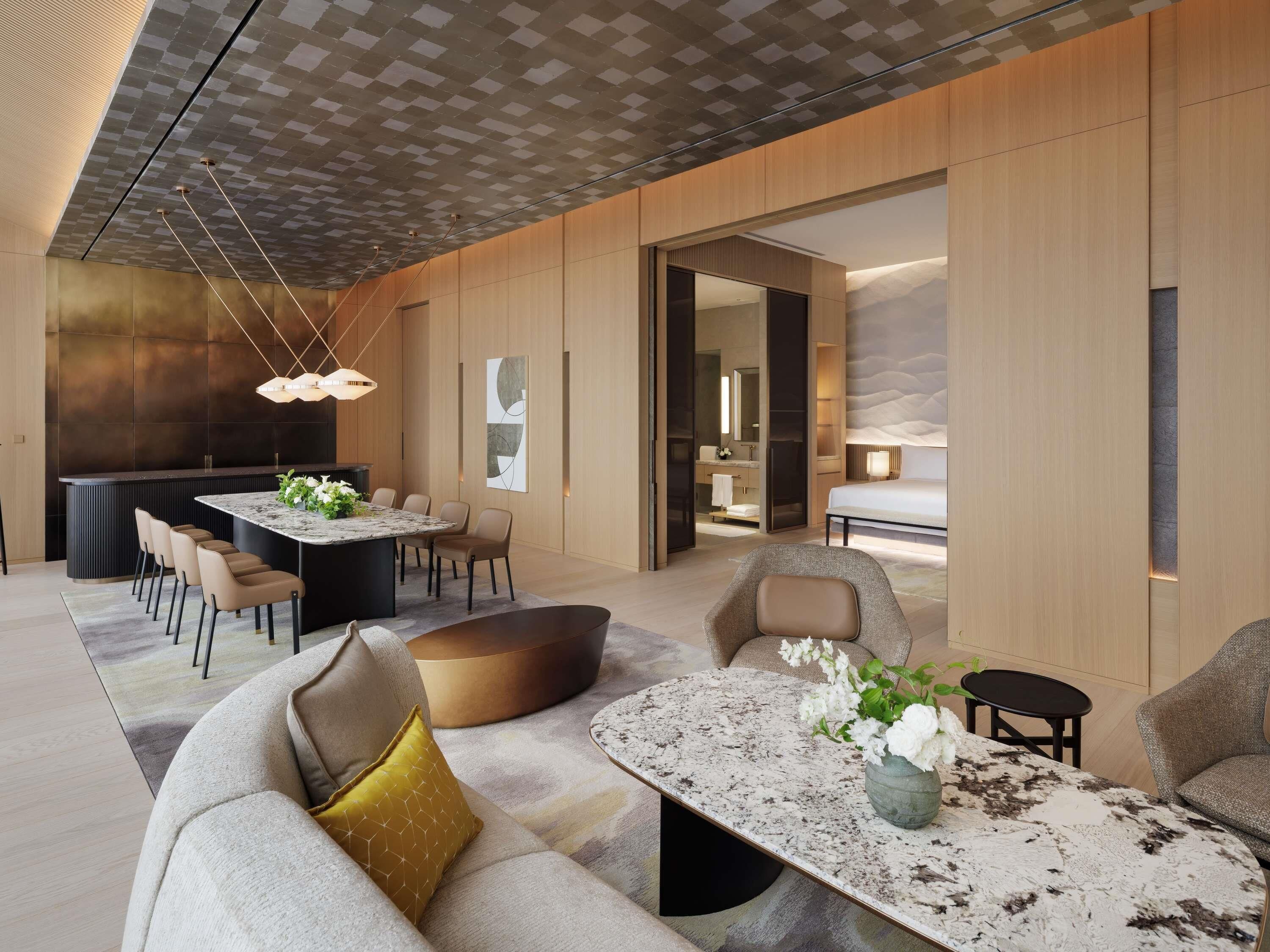 Una habitación de hotel moderna con comedor, sofá, mesa de centro y cama.