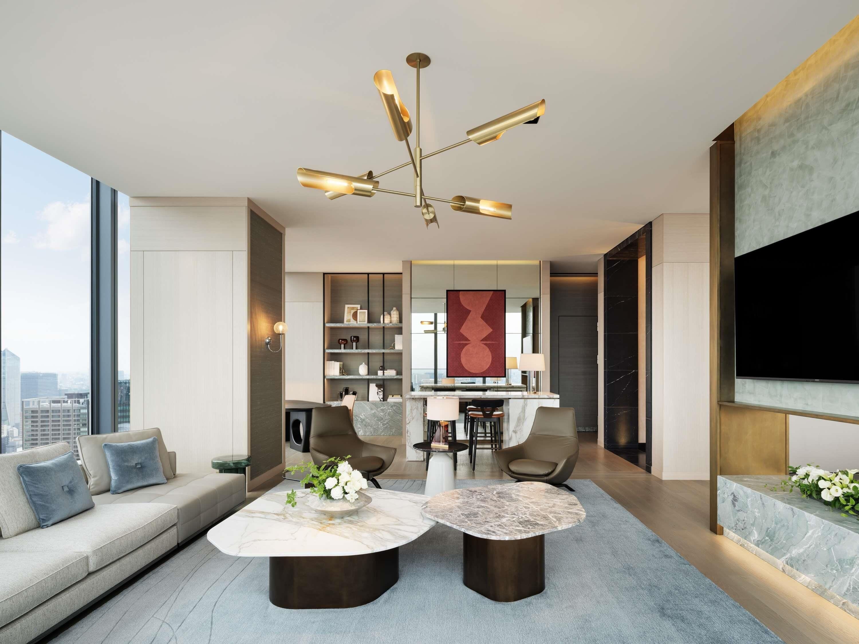A modern living room with a sofa, two coffee tables, a chandelier, and a TV.