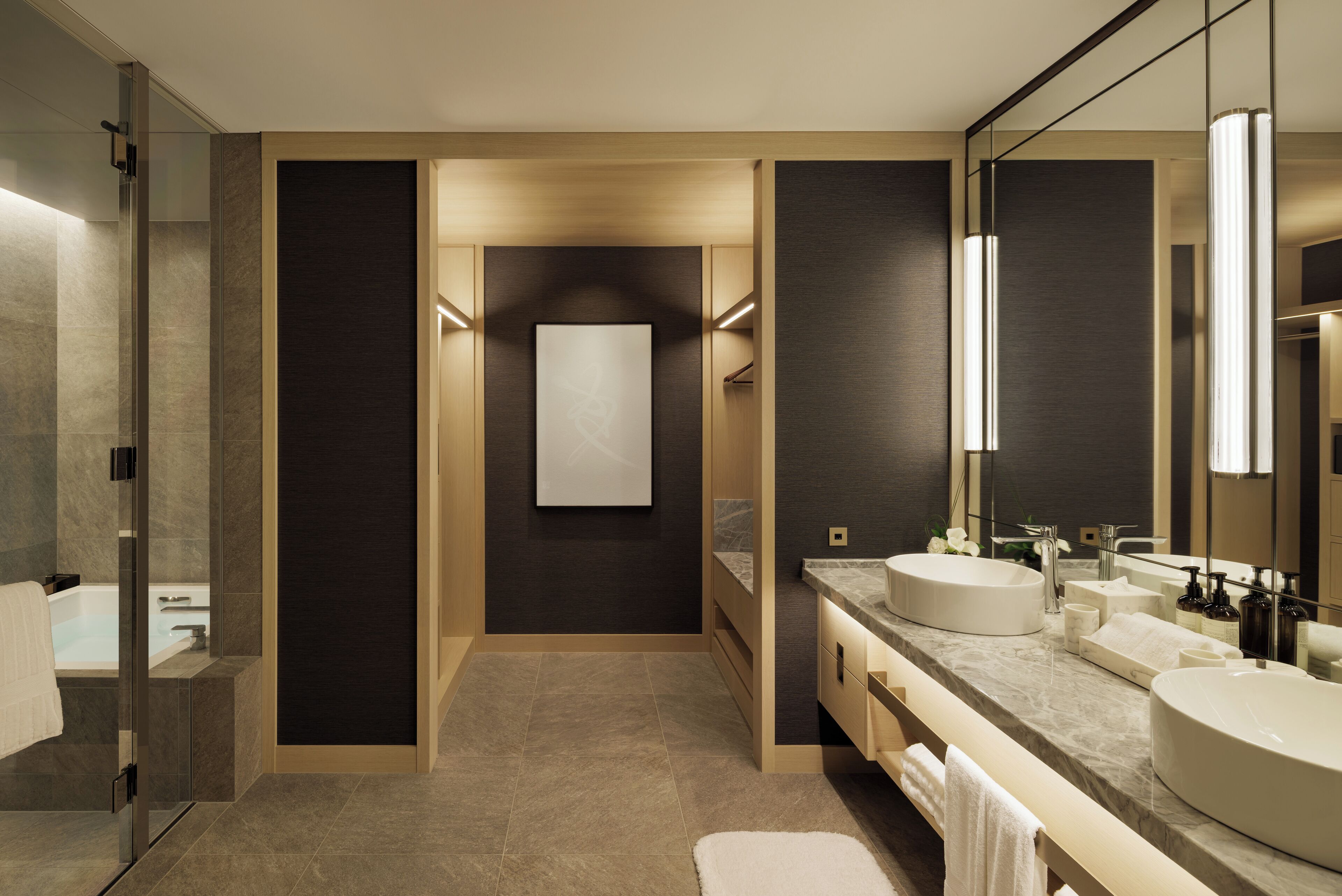 A modern bathroom with a glass shower, two sinks, a large mirror, and a neutral color scheme.