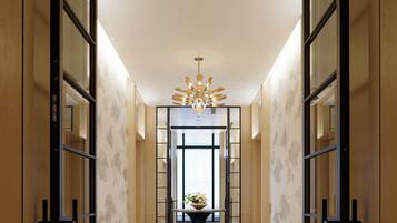 A modern hotel lobby with a central chandelier, mirrored walls, and a marble floor.