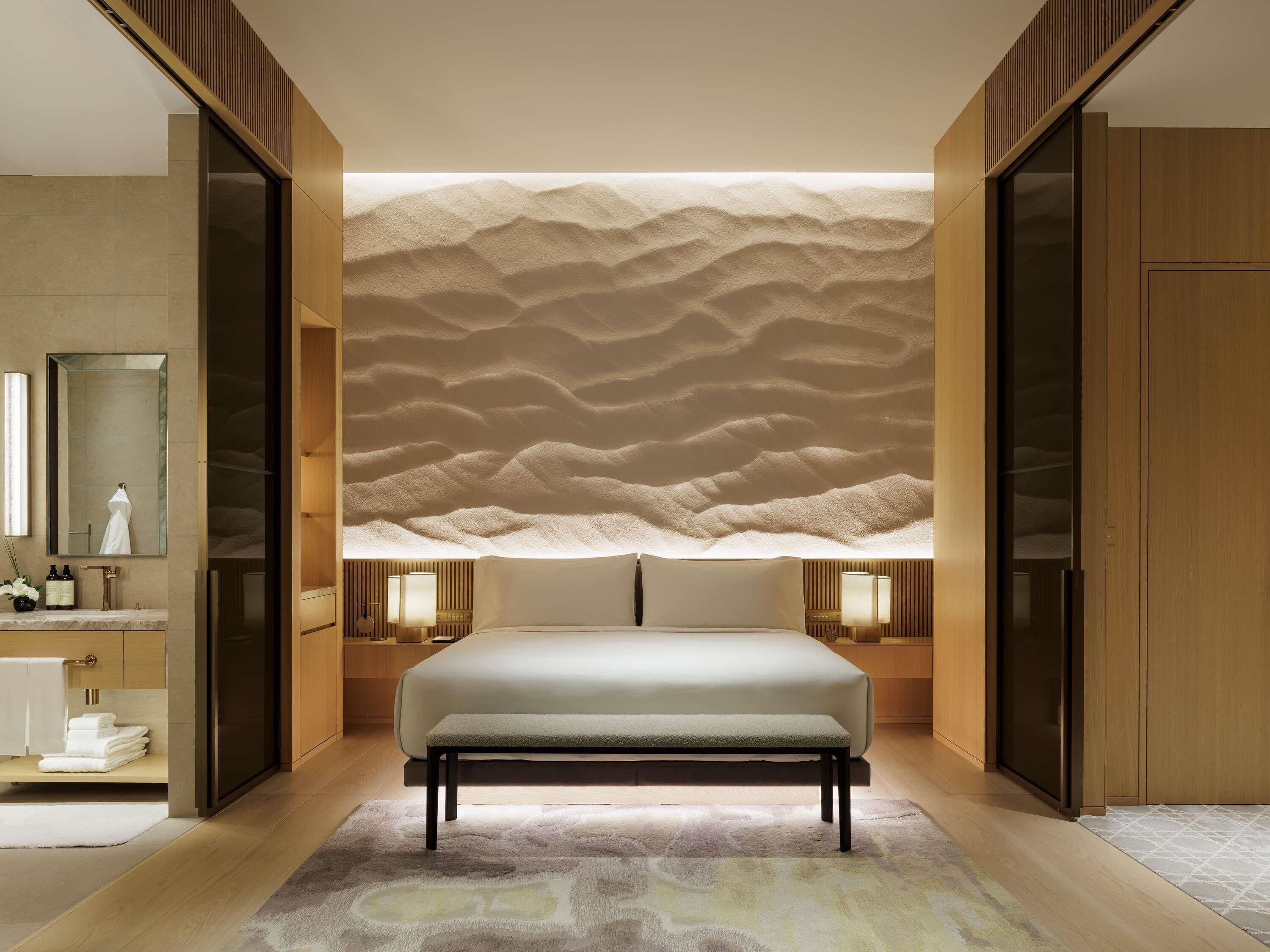 A modern bedroom with a large bed, a nightstand, a mirror, and a wardrobe.