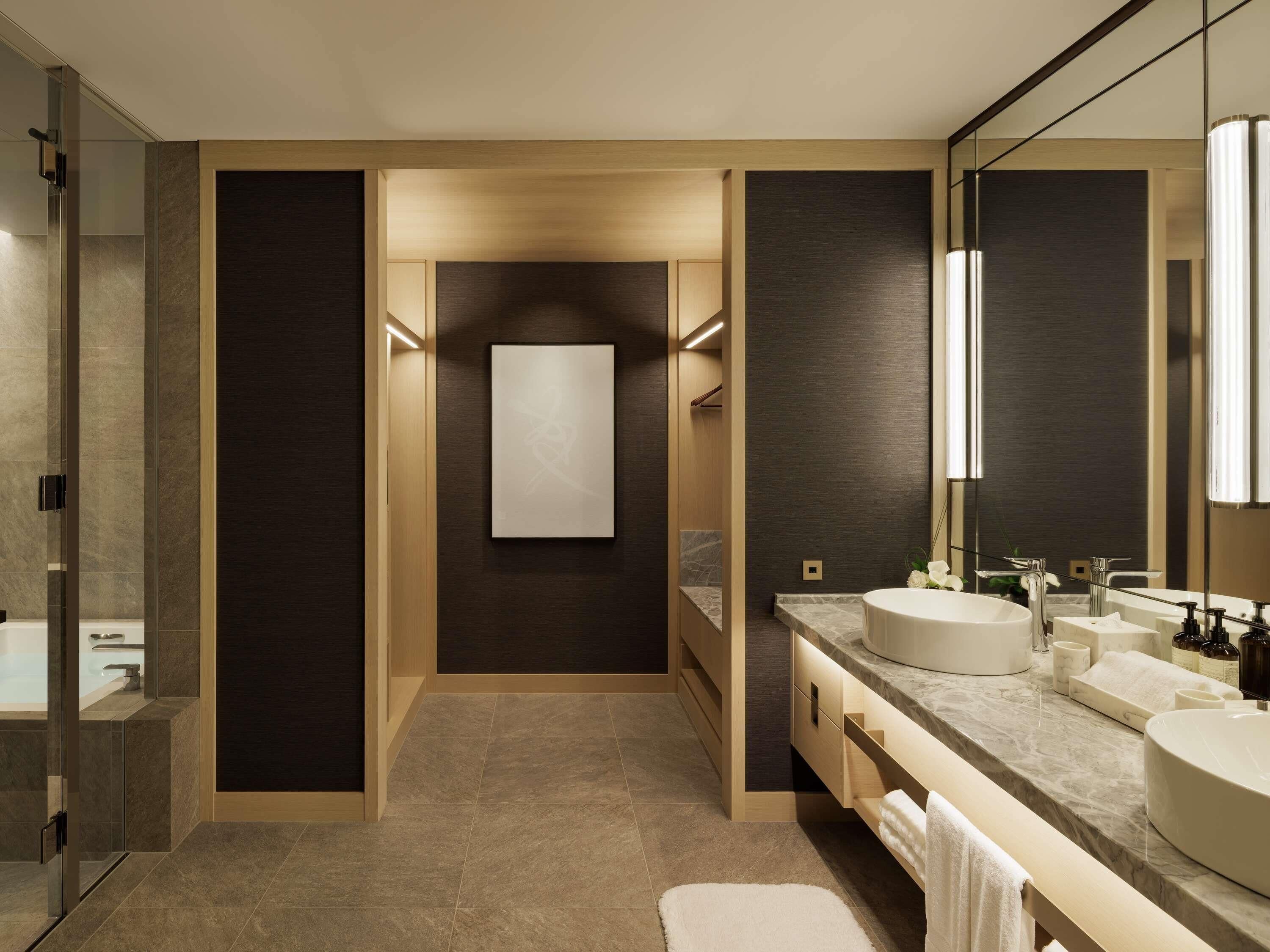 A modern bathroom with a glass shower enclosure, a large mirror, and a marble countertop.