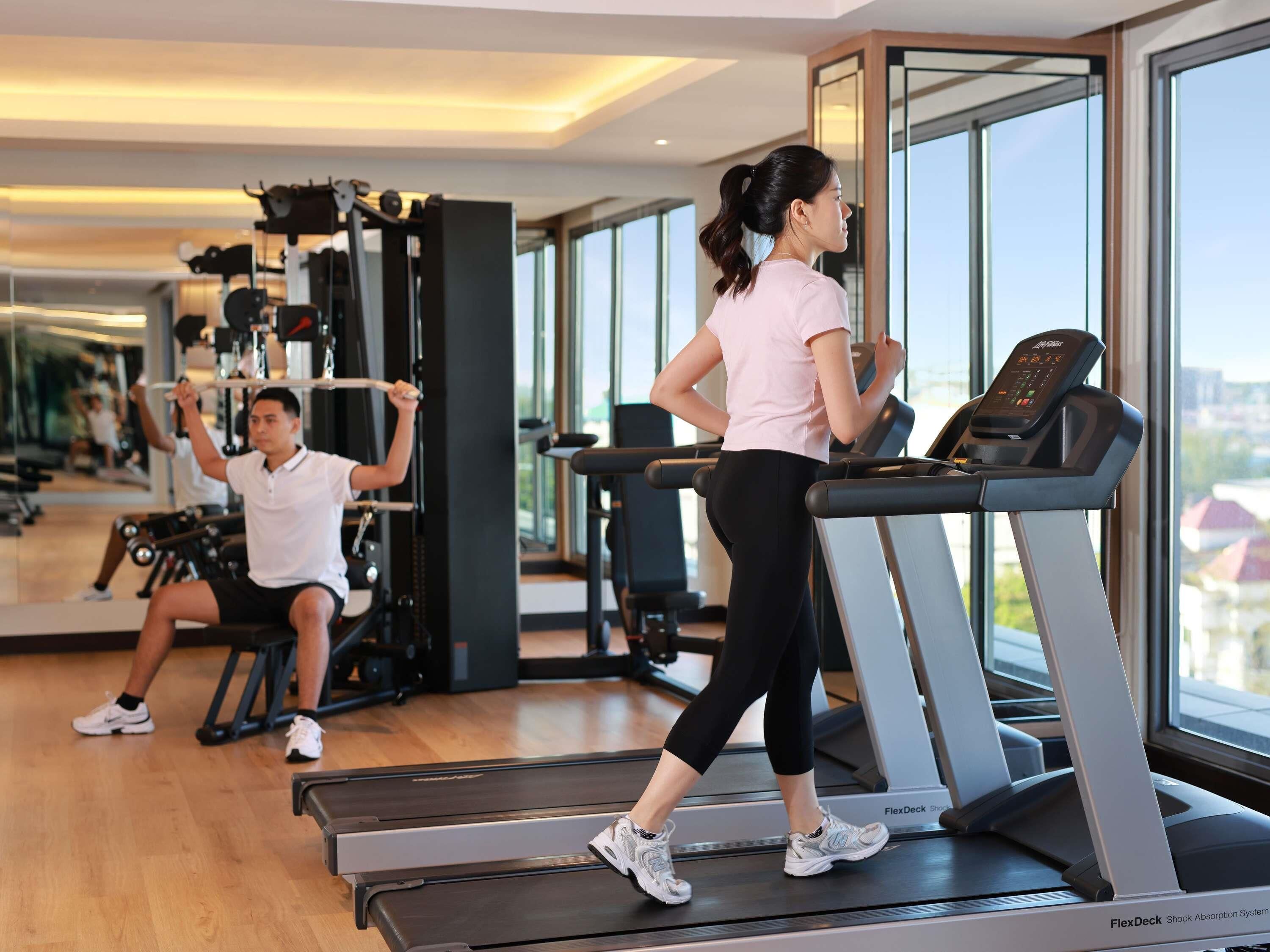 A gym with treadmills, weight machines, and a large mirror.