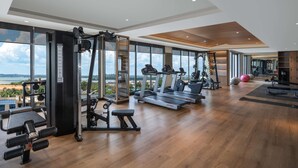 Une salle de sport équipée de machines de cardio, de matériel de musculation et de grandes fenêtres donnant sur l’extérieur.