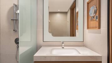 A modern bathroom with a glass shower enclosure, a large mirror, and a wooden vanity with a sink.