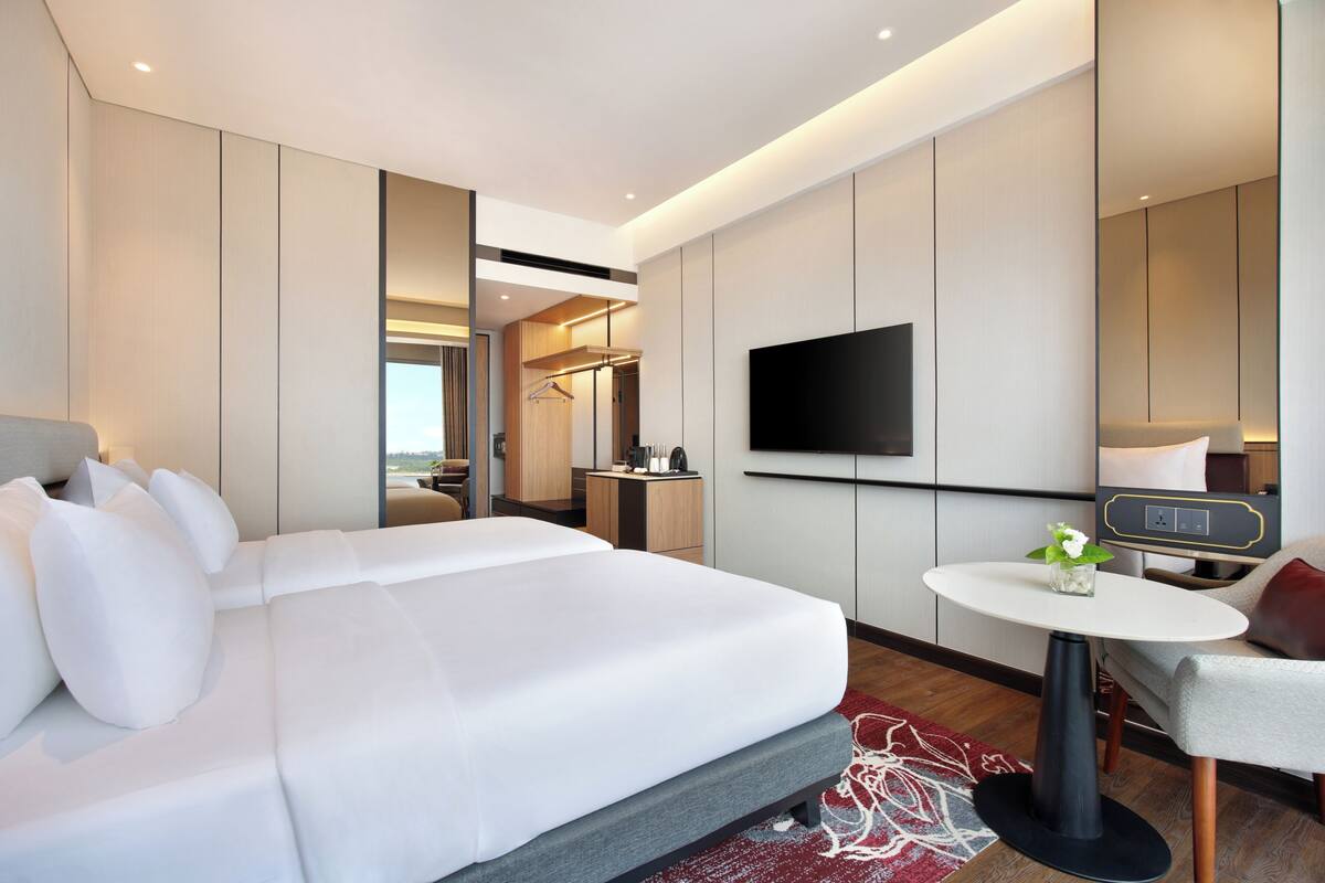 Une chambre d’hôtel moderne dotée d’un grand lit, d’un téléviseur à écran plat, d’une petite table ronde et d’un coin salon.