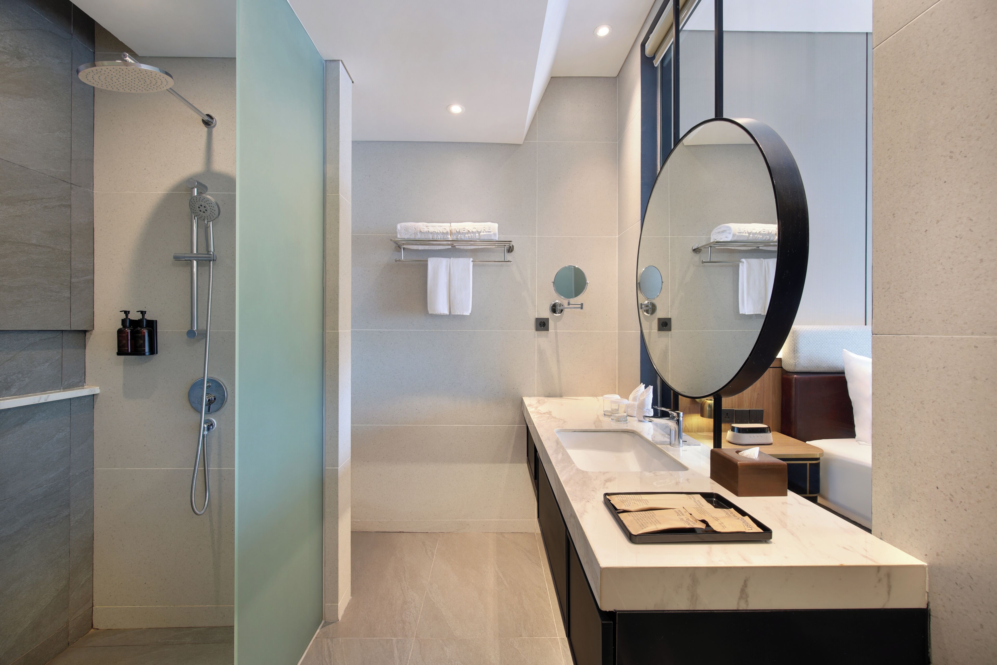 Un baño moderno con ducha, un espejo grande, un tocador con lavamanos y un perchero para toallas.