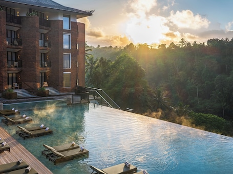 A resort with a swimming pool, lounge chairs, and a view of the surrounding forest.