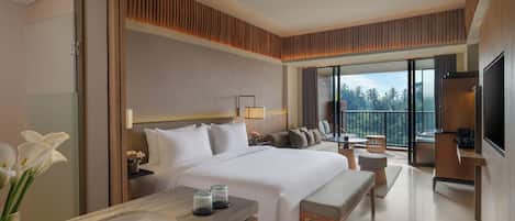 Habitación de hotel moderna con una cama grande, un área de descanso, un balcón con vistas y un televisor.