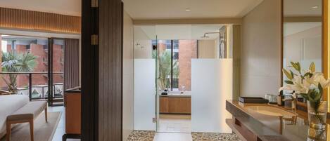 Una habitación de hotel moderna con una cama grande, un baño con ducha y vistas a la ciudad.