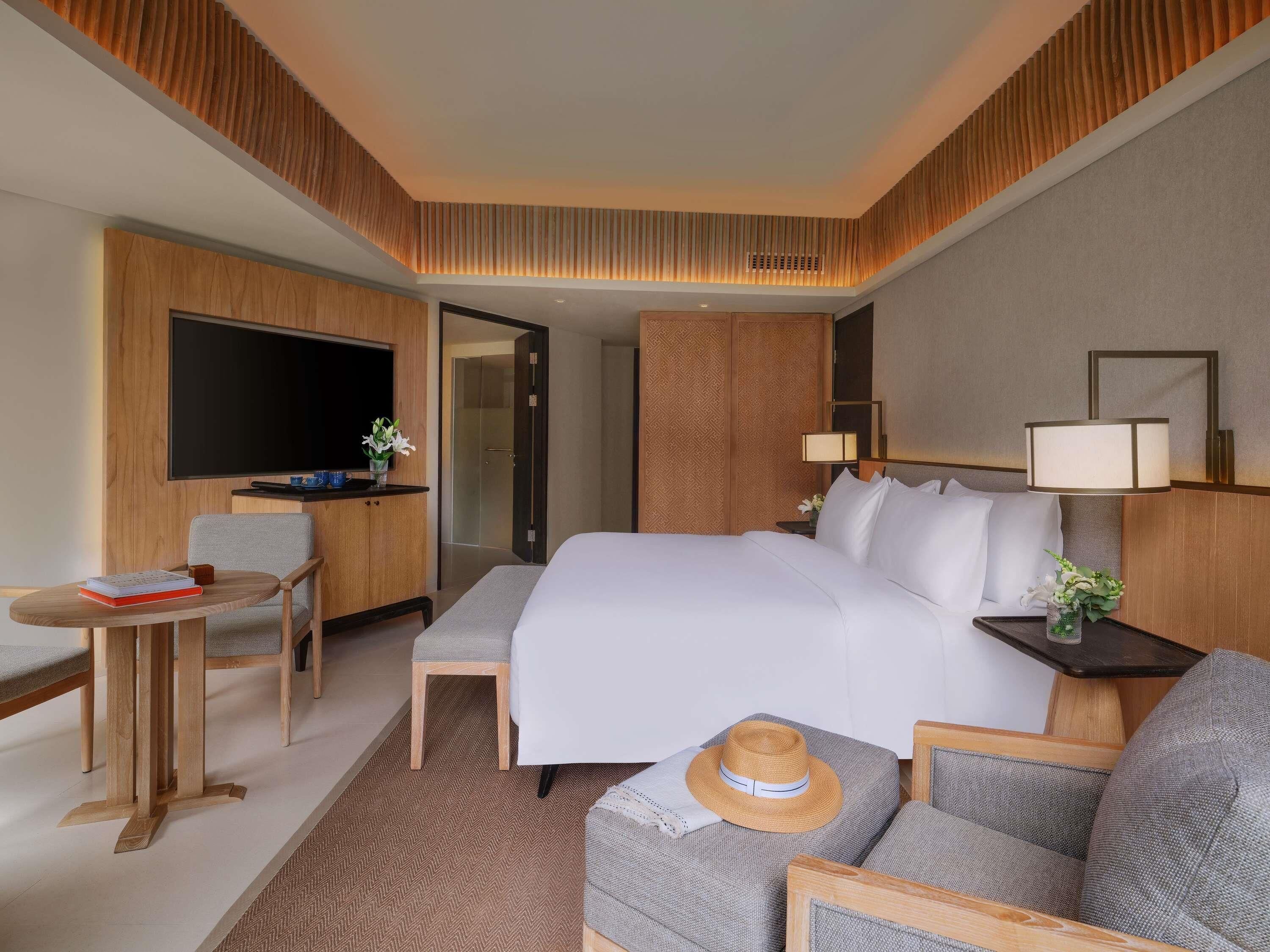 A hotel room with a bed, a desk, a TV, and a seating area.