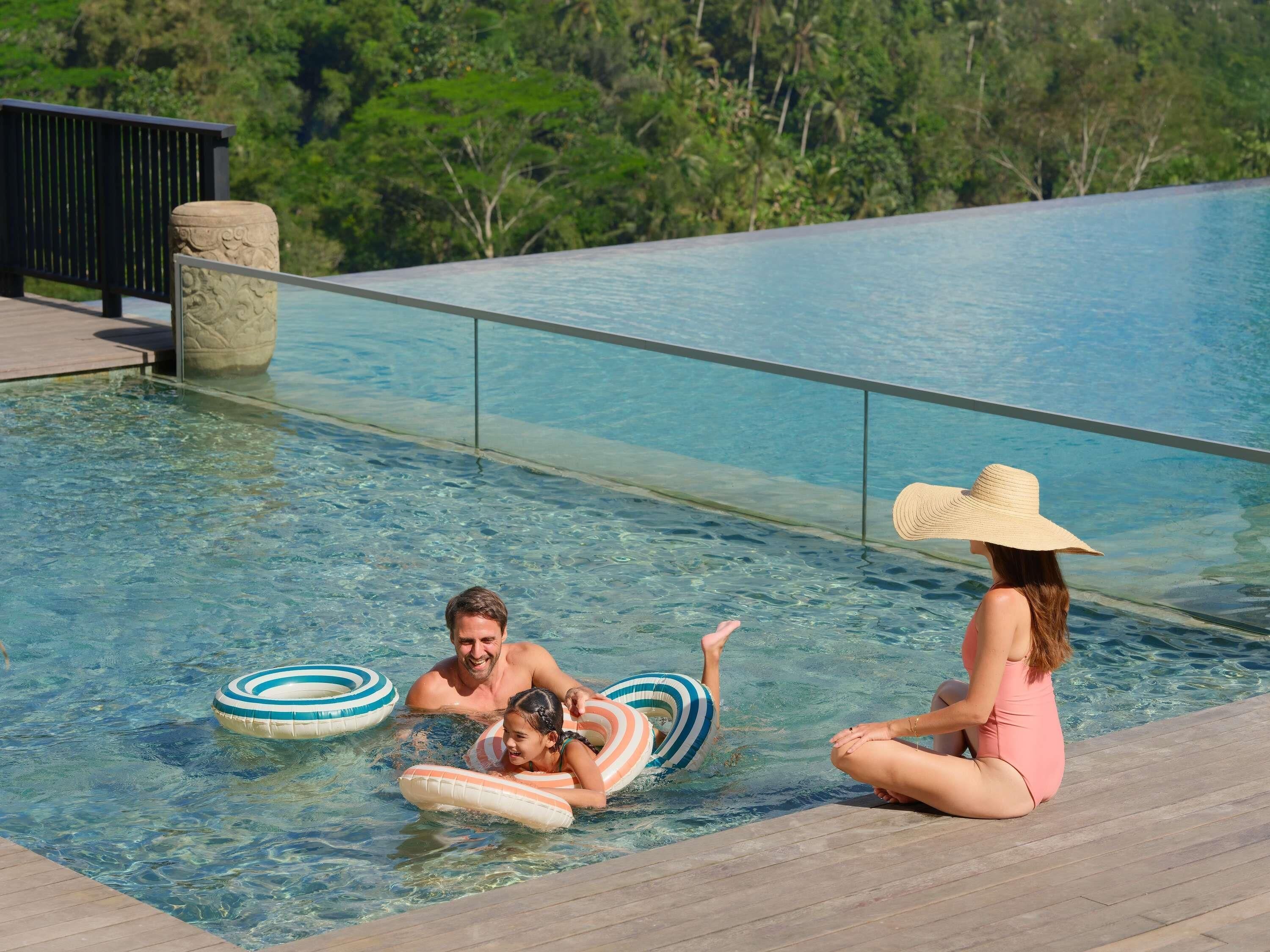 Ein Poolbereich mit klarem Wasser, einer Holzterrasse und einer Steinstruktur.