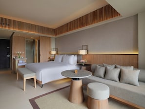 Una habitación de hotel moderna con una cama grande, un sofá, una mesita y un banco.