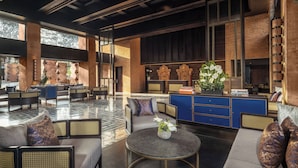 A spacious lobby with a mix of seating areas, a reception desk, and a decorative plant centerpiece. - Novotel Bali Ubud Resort (Payangan)