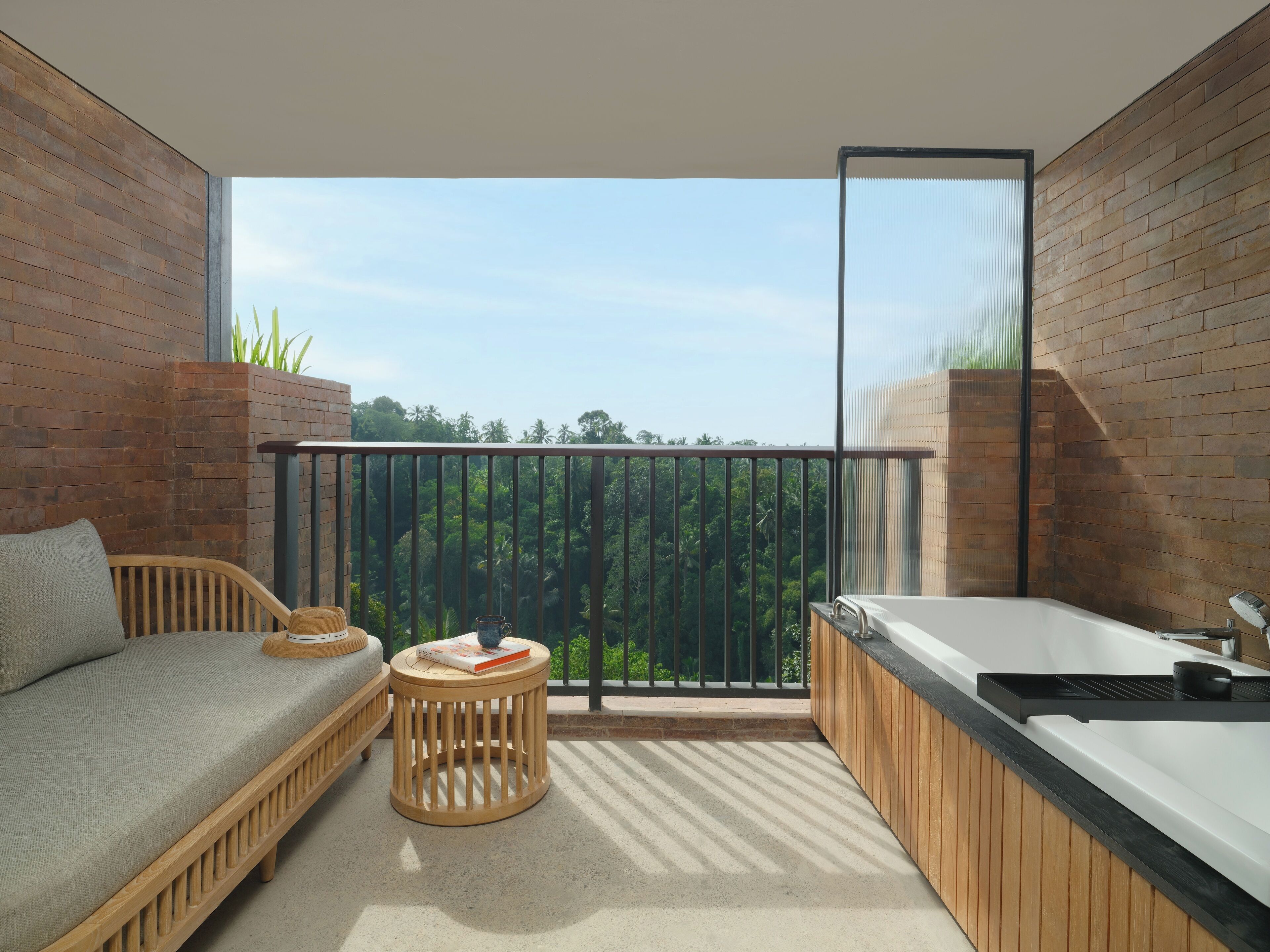 A balcony with a sofa, a small round table, and a bathtub.