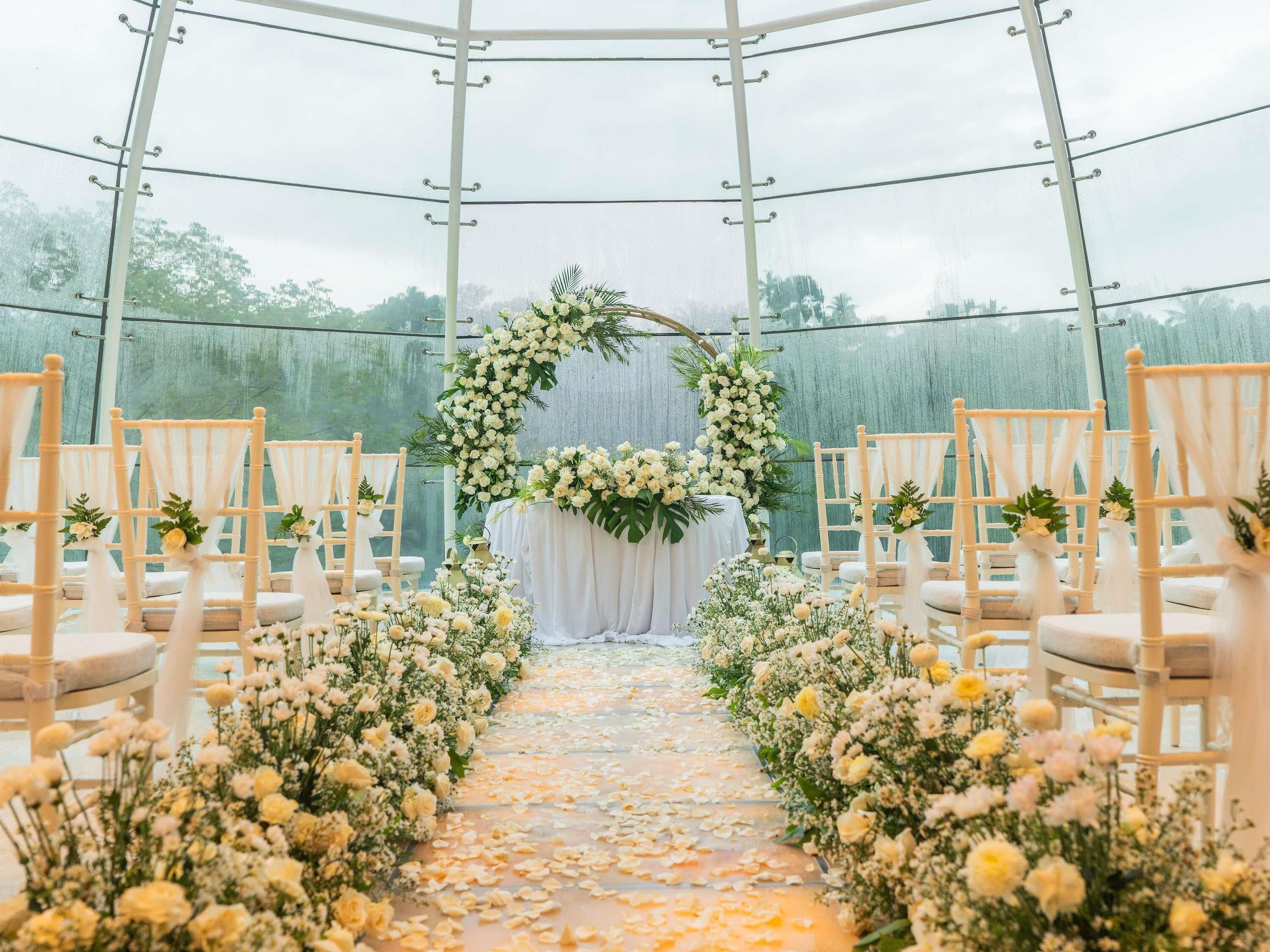Une allée bordée de chaises et agrémentée de compositions florales, menant à un autel décoré.