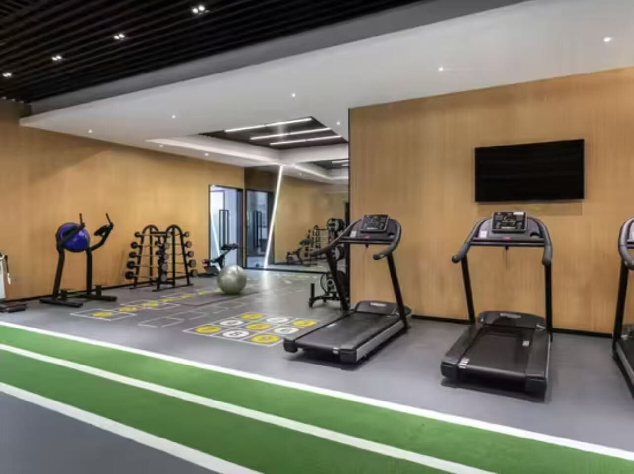 Ein Fitnessstudio mit Laufbändern, Übungsbällen und einem Gewichtecke.