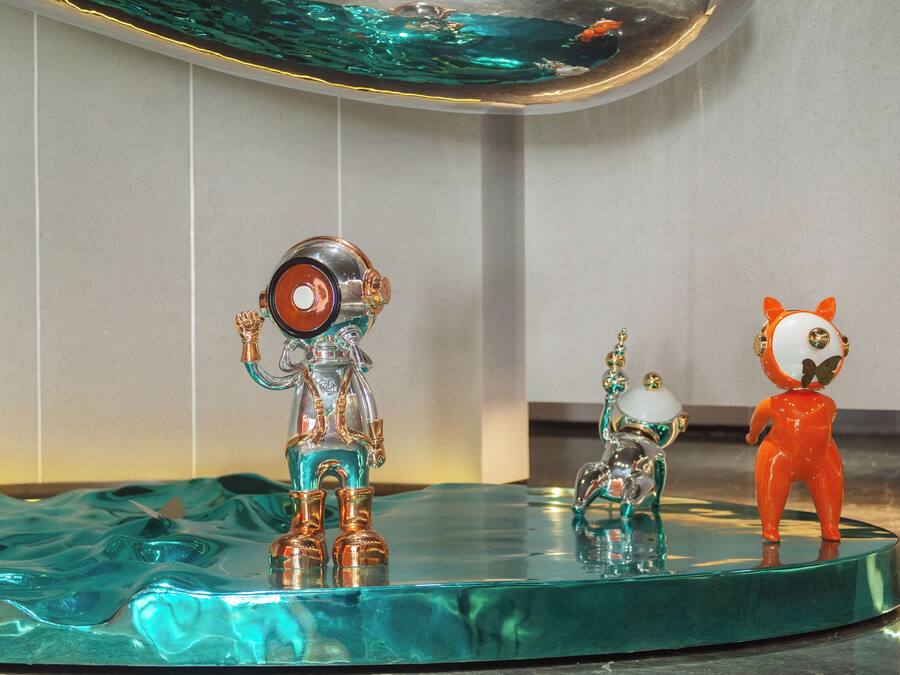 Een glazen tafel met drie decoratieve beeldjes.