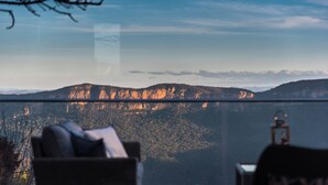 Habitación con vista a un paisaje montañoso a través de un muro de vidrio.