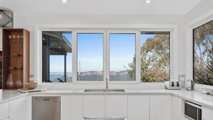 Una cocina moderna con lavavajillas, un ventanal con vistas al exterior y un cuenco de fruta en la encimera.