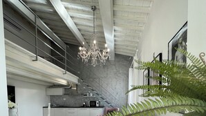 Un espacio de estar moderno con una escalera, una araña y un comedor.