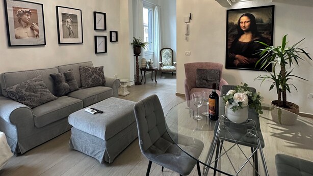 Una sala de estar moderna con un sofá gris, una mesa de centro de vidrio y una araña.