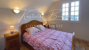 A bedroom with a bed, bedside lamps, a window, and a view of the outside. - Le Gîte des Sabotiers by Kastell Breizh (Canihuel)