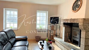 A living room with a fireplace, leather sofa, and a coffee table. - Le Gîte des Sabotiers by Kastell Breizh (Canihuel)