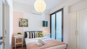 A modern bedroom with a bed, bedside tables, a wardrobe, and a large window. - Hue 1-Bedroom Apartment in Larnaca (Larnaca)