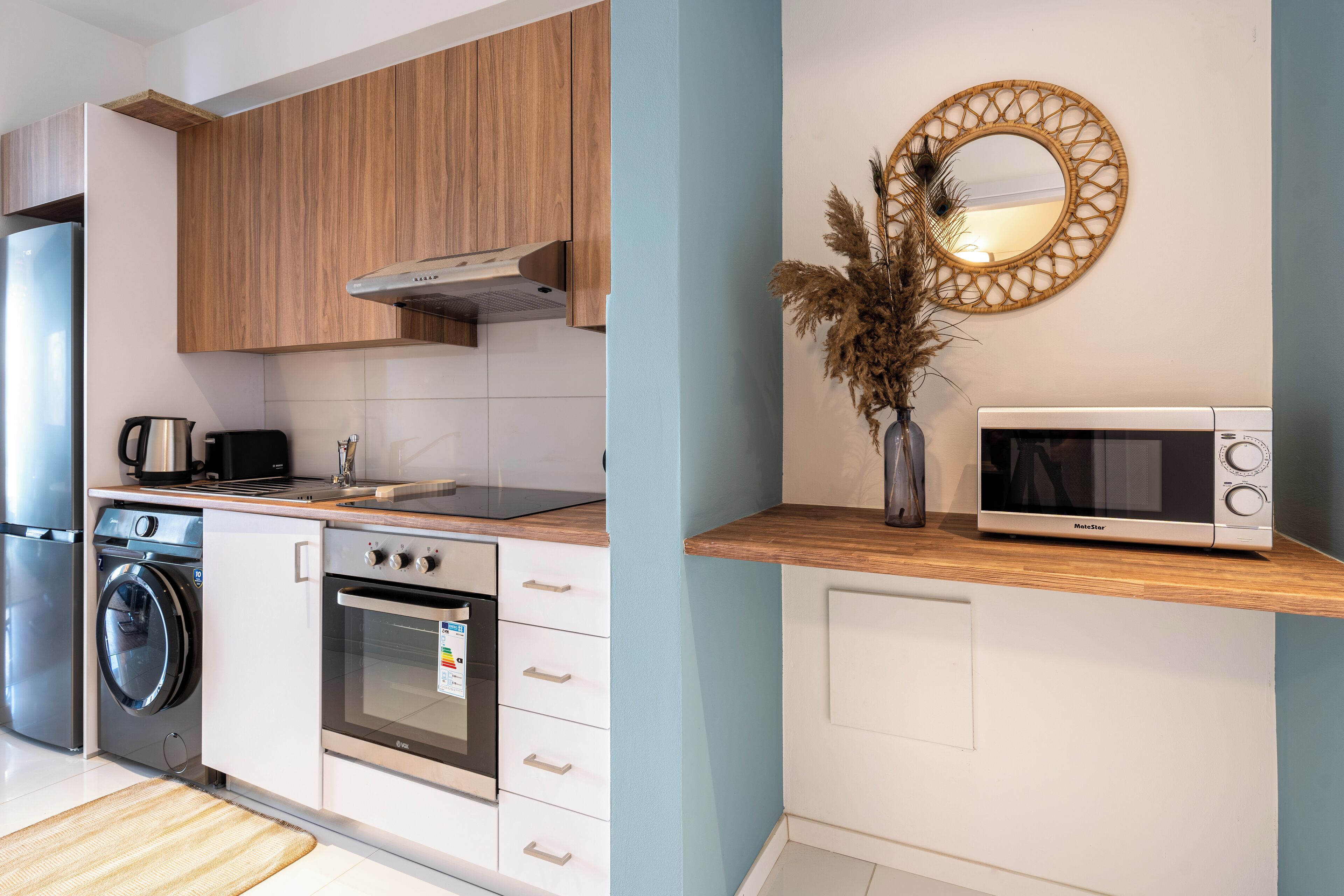 Eine moderne Küche mit Holzausstattung, Backofen, Mikrowelle und Waschmaschine.