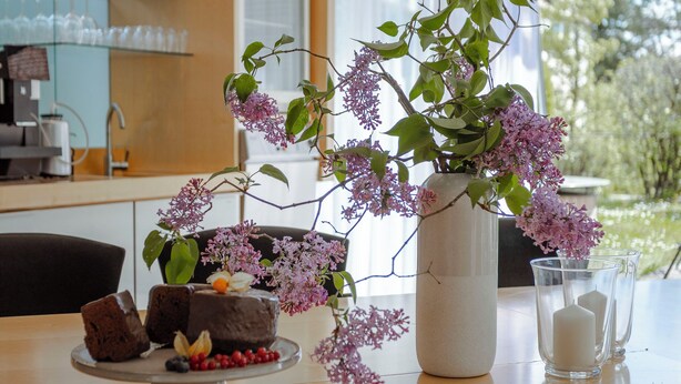 Uma mesa de jantar com um vaso de flores, um bolo e uma vela.