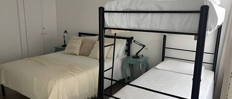 Habitación con literas, escritorio, silla, lámpara y armario.