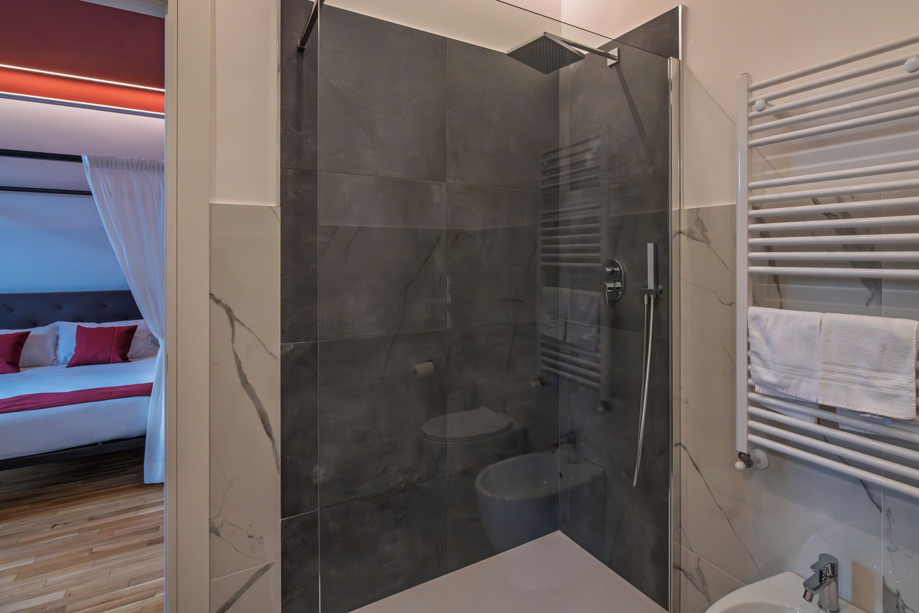 A modern bathroom with a glass-enclosed shower, a white sink, and a towel rack.