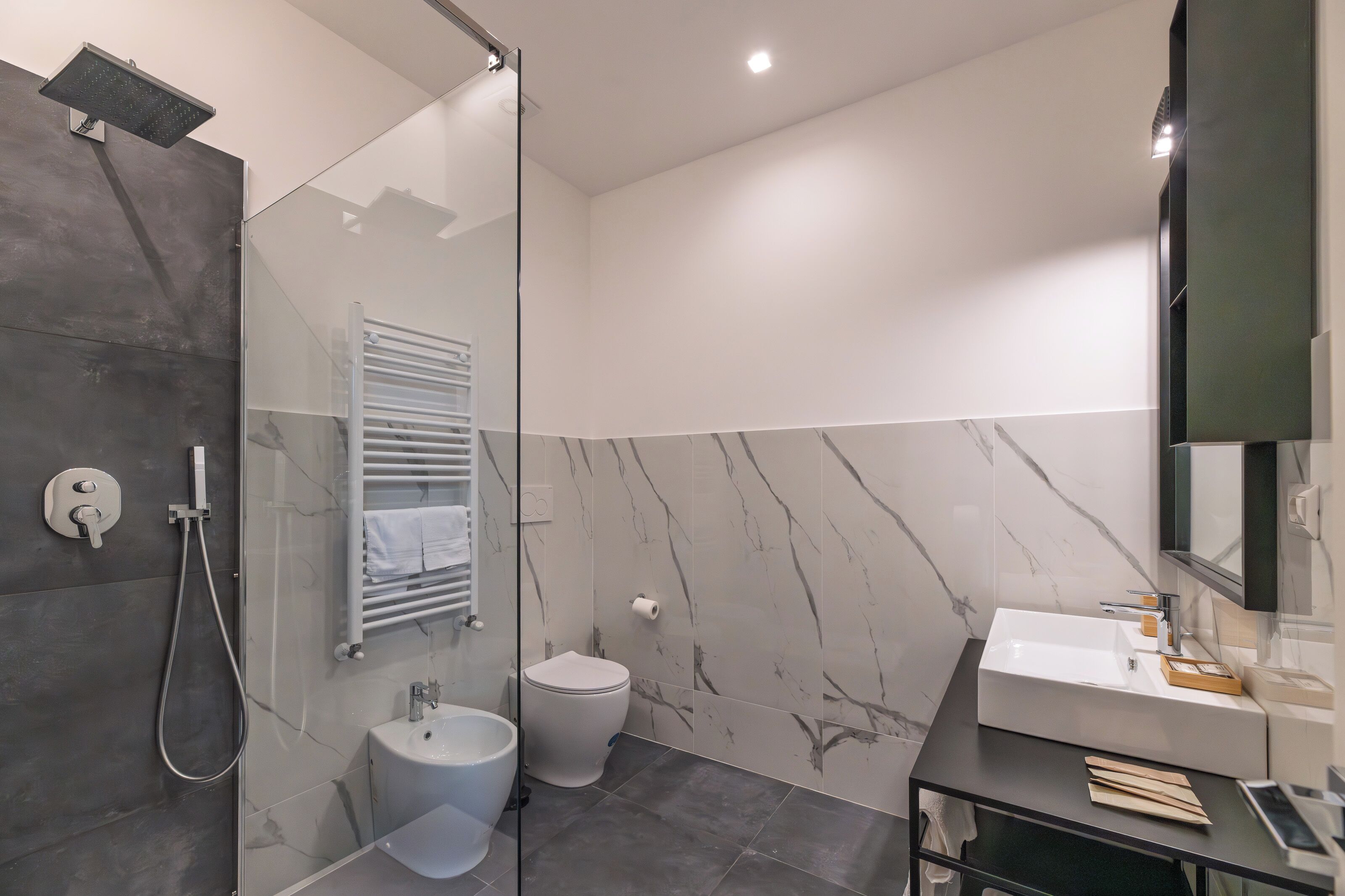 Un baño moderno con cabina de ducha de vidrio, inodoro blanco y tocador con lavabo y espejo.