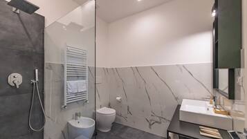 Un baño moderno con cabina de ducha de vidrio, inodoro blanco y tocador con lavabo y espejo.
