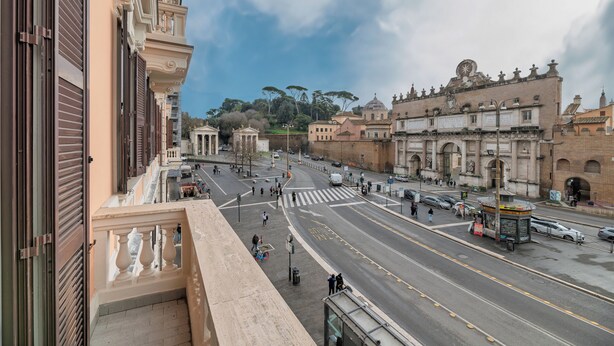 Vista de calle con un edificio de arquitectura clásica, cielo despejado y un paso de peatones.