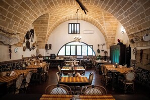 A restaurant with a high arched brick ceiling, multiple tables and chairs, and a large window with a view. - Masseria Scianne (Nardò)