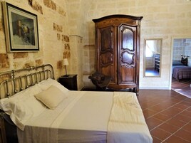 Un dormitorio con cama, armario de madera, un cuadro en la pared y suelo de baldosas.