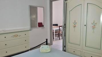 Un dormitorio con cama, cómoda, espejo y armario.