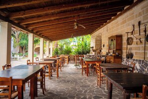 An outdoor dining area with stone flooring and wooden tables and chairs. - Masseria Scianne (Nardò)