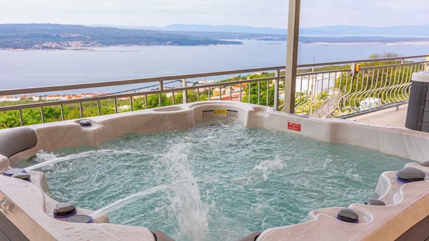 A hot tub with a view of a lake and distant mountains.