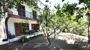 A courtyard with a small tree, a patio with outdoor furniture, and a building with a balcony. - Cozy Igalo Retreat Ideal for Families (Igalo)