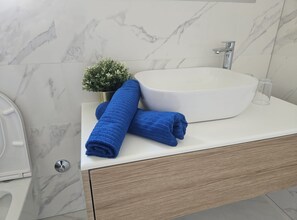 A bathroom with a white marble sink, a wooden cabinet, and a small potted plant. - Villa Magnolia Pirovac (Pirovac)